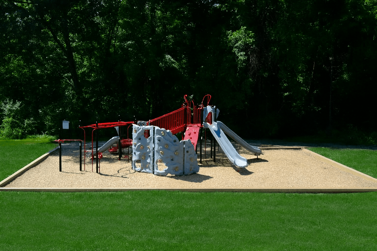 A playground with a slide, swings, and a climbing wall.